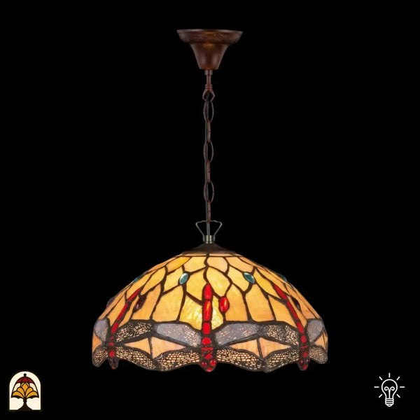 Verlichte Tiffany hanglamp Libelle aan bronzen ketting met plafondbak, koepelvormige geel-amber kap met rode druppelvormige en blauwe ronde accenten in glas-in-lood, libellenmotieven langs de rand, donkere achtergrond