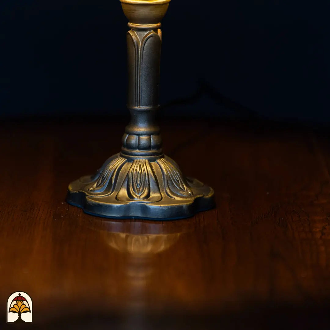 Close-up voet — bronzen klassieke kandelaarvoet met bloemblad-decoraties op ronde gebogen basis op houten oppervlak