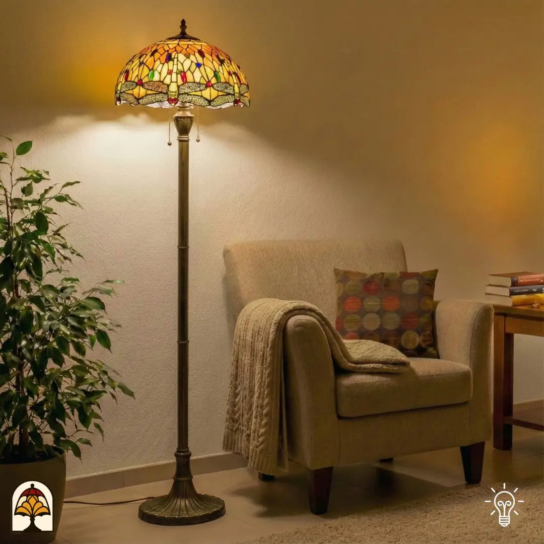 Tiffany vloerlamp met amberkleurig glas brandt naast een fauteuil in een warme woonkamer