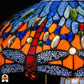 Detailopname van tiffany lamp libelle-rand onderaan de kap verlicht, lavendelblauw-witte libellen met geaderde vleugels in glas-in-lood, rode libellen zichtbaar, blauwe en amber glaskralen