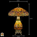 Tiffany lamp tafellamp met maatindicaties: diameter kap 46 cm, totale hoogte 68 cm, voetdiameter 17 cm; verlichte kap met libellemotieven, amberkleurig glas en blauwe glaskralen zichtbaar