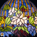 Close-up verlichte kap Tiffany tafellamp Pond Lilia, witte waterlelie met roze accenten, groene bladeren, rode en blauwe ronde glasaccenten op blauwe en gele verticale strepen