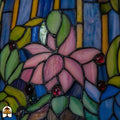 Close-up onverlichte kap Tiffany tafellamp Pond Lilia, roze waterlelies en groene bladeren, gekleurde ronde glasaccenten op blauwe en gele strepen