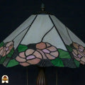 Close-up onverlichte kap Tiffany tafellamp Alba Sereno, roze rozen en groene bladeren, grijze geribbelde randpanelen