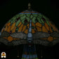 Close-up onverlichte kap Libellula Lumina ⌀30, groene en oranje glas-in-lood panelen met rode, groene en amber juwelen, blauwe libellenfries langs rand