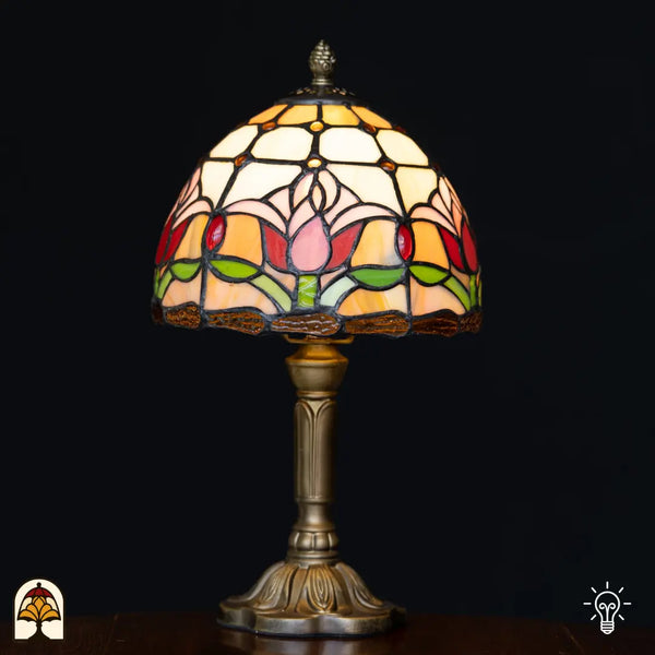 Verlichte Tiffany tafellamp Tulipa ⌀20 cm op zwarte achtergrond – koepelkap met roze en rode tulpen op crème en oranje glas-in-lood, bronzen kolomvoet