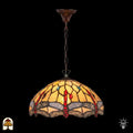 Verlichte Tiffany hanglamp Libelle aan bronzen ketting met plafondbak, koepelvormige geel-amber kap met rode druppelvormige en blauwe ronde accenten in glas-in-lood, libellenmotieven langs de rand, donkere achtergrond