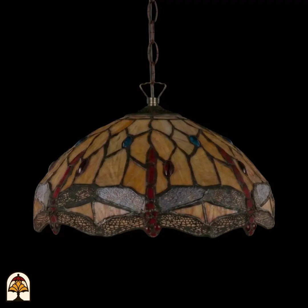 Onverlichte Tiffany hanglamp Libelle aan bronzen ketting, koepelvormige geel-amber kap met libellenmotieven langs de rand, donkere achtergrond