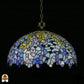 Onverlichte Tiffany hanglamp Drizzle Bleu ⌀50 op donkere achtergrond, lila-blauwe en turquoise koepelkap met gele bladaccenten en geschulpte rand, bronzen ketting