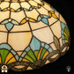 Close-up bovenzijde kap Barok ⌀40, crème glas-in-lood panelen met gele en blauwe bloemvormen, blauw-groene waaier, bronzen sierrand onderaan