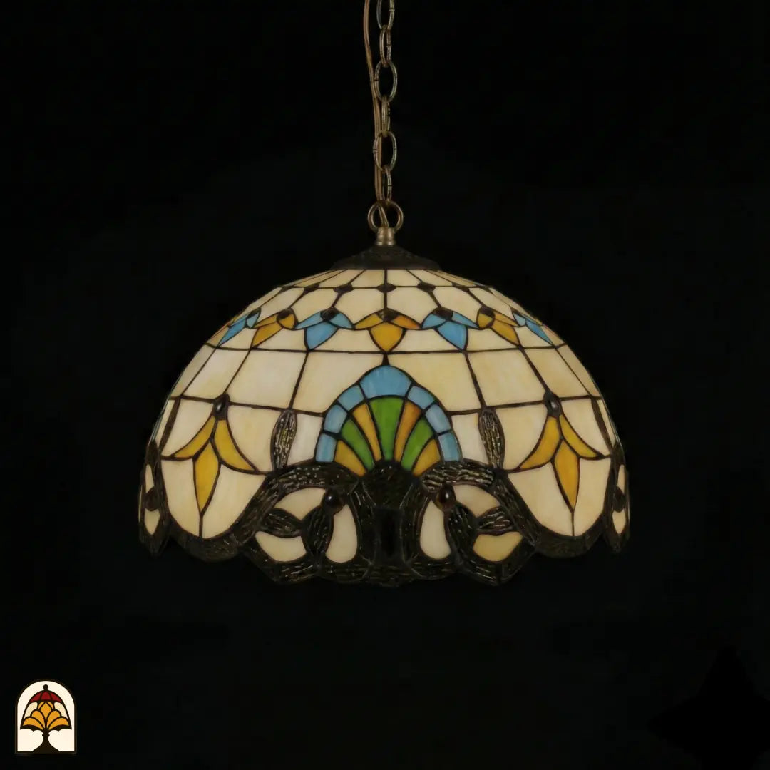 Onverlichte Tiffany hanglamp Barok ⌀40 op donkere achtergrond, kap met crème panelen, gele tulpmotieven, blauwe en groene accenten, donkere barok rolwerkrand onderaan, bronzen ketting