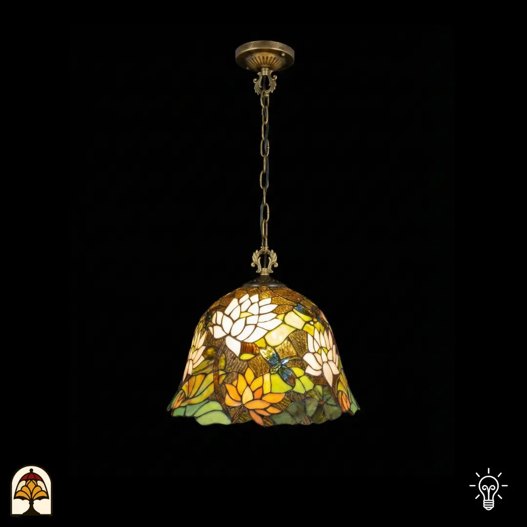 Tiffany lamp hanglamp verlicht, klokvormige glas-in-lood kap met witte lotusbloemen, oranje-gele lotusbloemen, groene waterleliebladen en een libelle op bruinamberen achtergrond, gekartelde rand, opgehangen aan bronzen ketting met sierlijke plafondrozet
