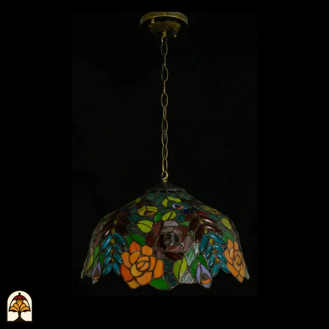 Tiffany lamp hanglamp onverlicht, volledig beeld met bronzen plafondrozet en bronzen ketting, koepelvormige kap met oranje en roze rozen en gekleurde bladeren in glas-in-lood, gekartelde rand