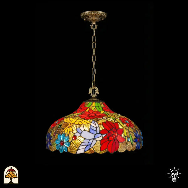 Tiffany lamp hanglamp verlicht met koepelvormige glas-in-lood kap, rode poinsettia-bloemen, blauwe madeliefjes, wit-lavendel vlindermotief en gele bladpanelen op goudkleurige achtergrond, gekartelde rand, opgehangen aan bronzen ketting met sierlijke plafondrozet