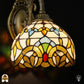 Close-up van de barokke Tiffany kap met goudgele bladvormen, blauwe vlakken, groene accenten en rode ovale steen in glas-in-lood