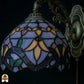 Onverlichte kap Tiffany wandlamp Royal Mosaic close-up – lavendelblauw, oranje en groen glas-in-lood met paarse iris en donkere loodlijnen