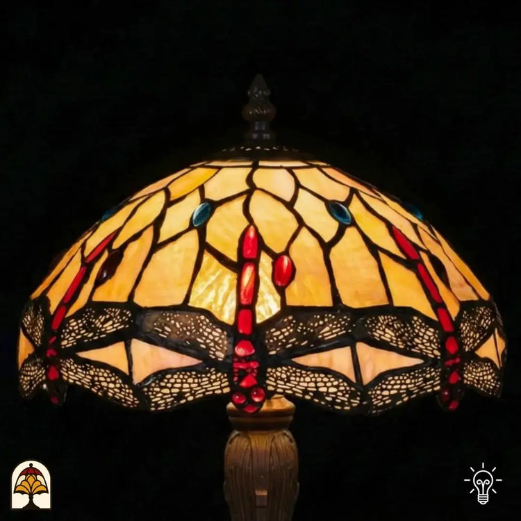 Close-up verlichte kap Tiffany tafellamp Libelle Elegance, geel-amber glas-in-lood met rode druppels en blauwe accenten, libellenmotieven langs de rand