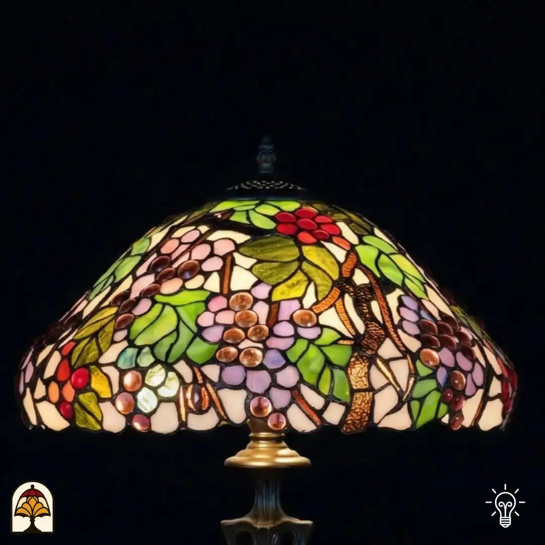 Close-up verlichte kap Tiffany tafellamp Sylva Berria van onderaf, wijnrankmotieven met rode en lila druiventrosjes en groene bladeren in glas-in-lood