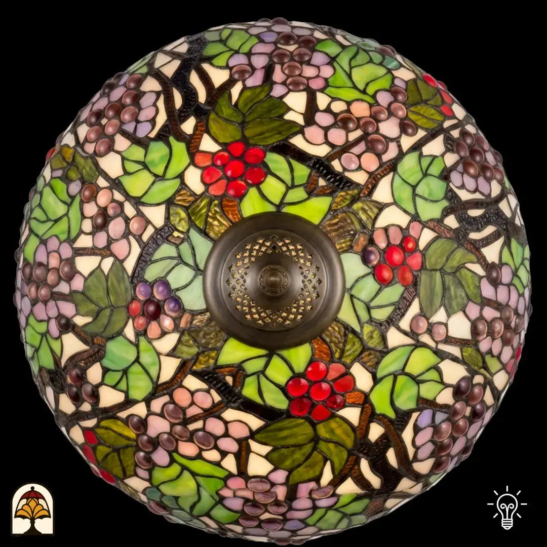 Bovenaanzicht verlichte koepelkap Tiffany tafellamp Sylva Berria, wijnrankmotieven met rode druiven, lila en beige druiventrosjes en groene bladeren, centrale bronzen fitting zichtbaar