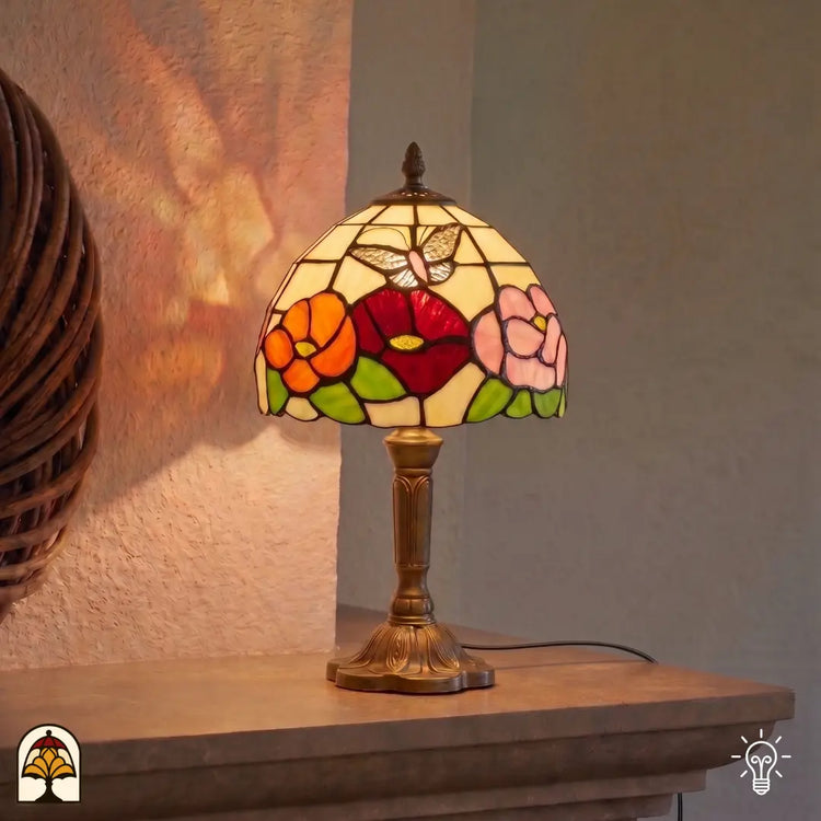 Tiffany tafellamp Papilio Reginae in interieur verlicht – bloemrijke tuin in glas-in-lood