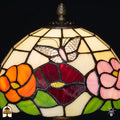 Close-up lampenkap Papilio Reginae – oranje, rood en roze bloemen met vlinder in glas