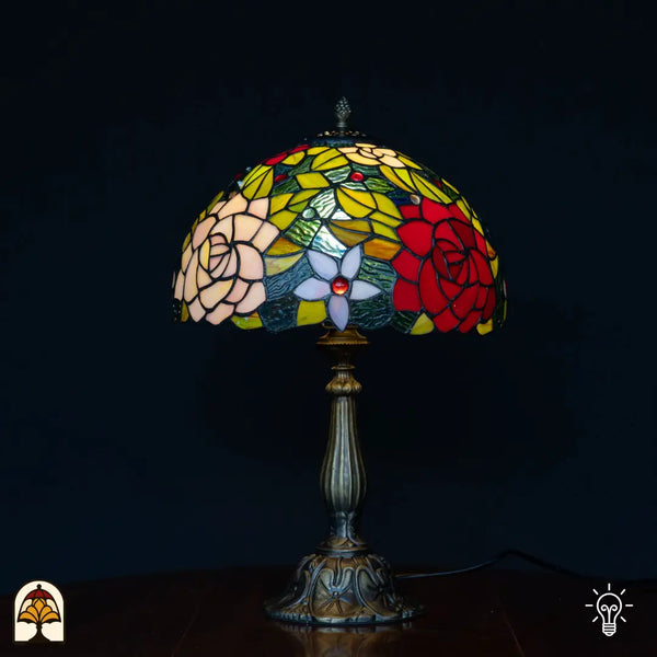 Verlichte Tiffany lamp tafellamp Rosetta ⌀30 cm op zwarte achtergrond – koepelkap met rozetmotief in glas-in-lood, bronzen kolomvoet